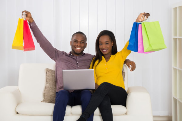 Young African Couple With Shopping Bags And Laptop